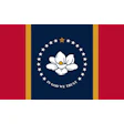 Mississippi state seal featuring white magnolia flower with gold star on navy blue circle surrounded by stars, with 'IN GOD WE TRUST' text