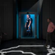 Modern corridor with neon blue lighting where visitors view an athlete displayed on an illuminated screen