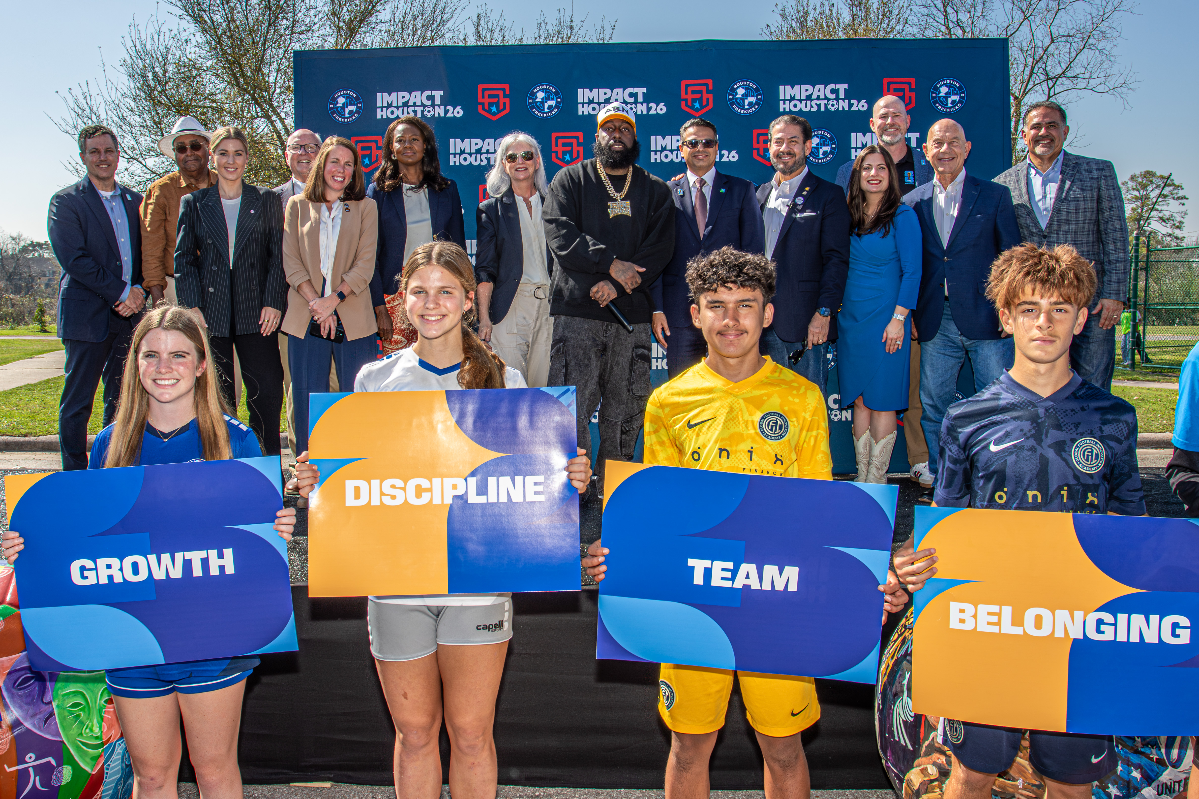 Group of young athletes and university officials holding motivational signs at a Houston sports event