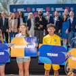 Group of young athletes and university officials holding motivational signs at a Houston sports event