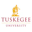 Tuskegee University logo featuring golden torch-bearing figure emblem above maroon text wordmark