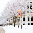 Snow-covered campus quad with frost-laden trees and Syracuse University banners on historic white building