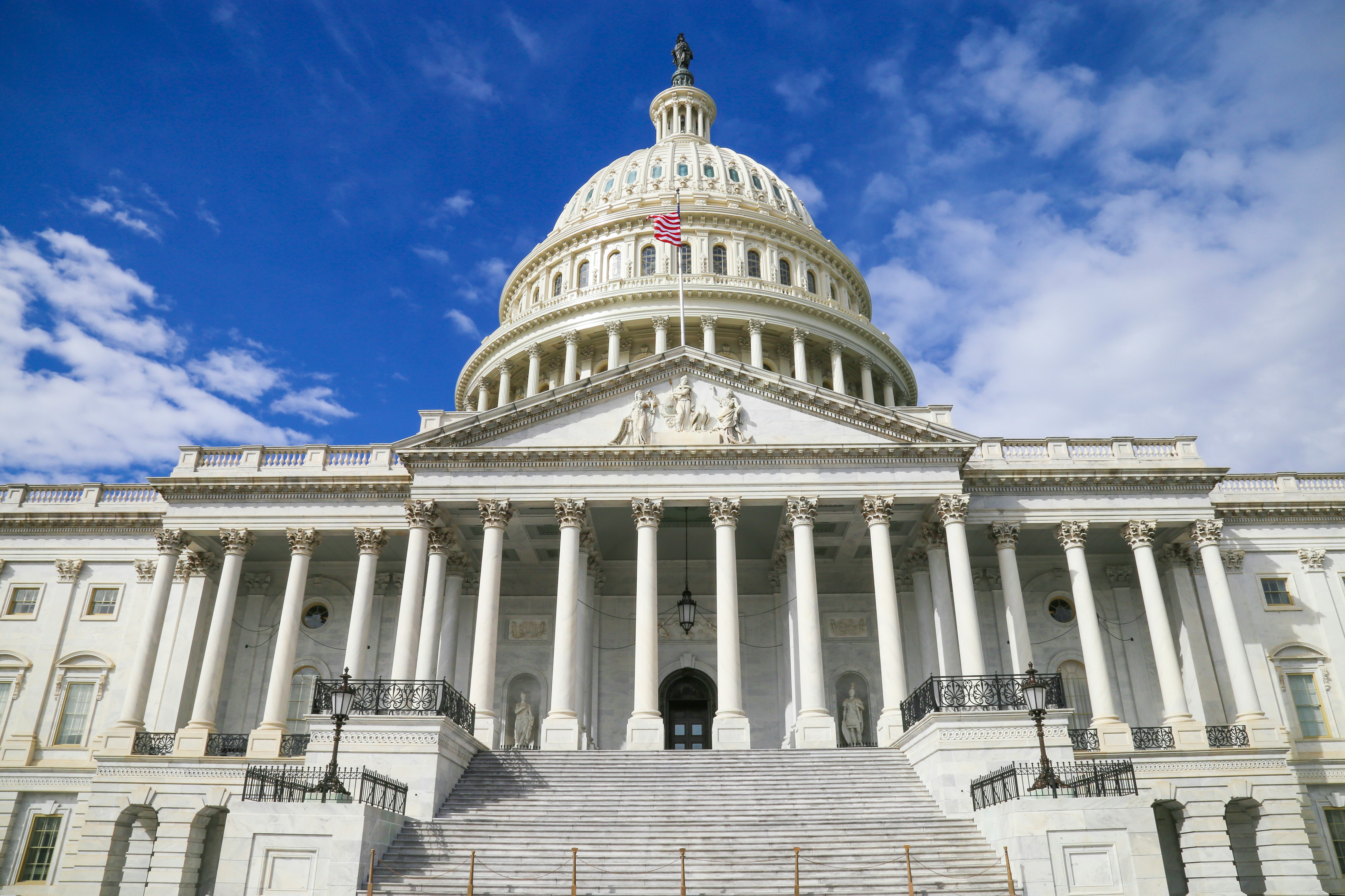 U.S. Capitol Building with white dome and classical columns against blue sky