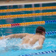 Competitive swimmer performing butterfly stroke in Olympic-style lap pool with colored lane dividers
