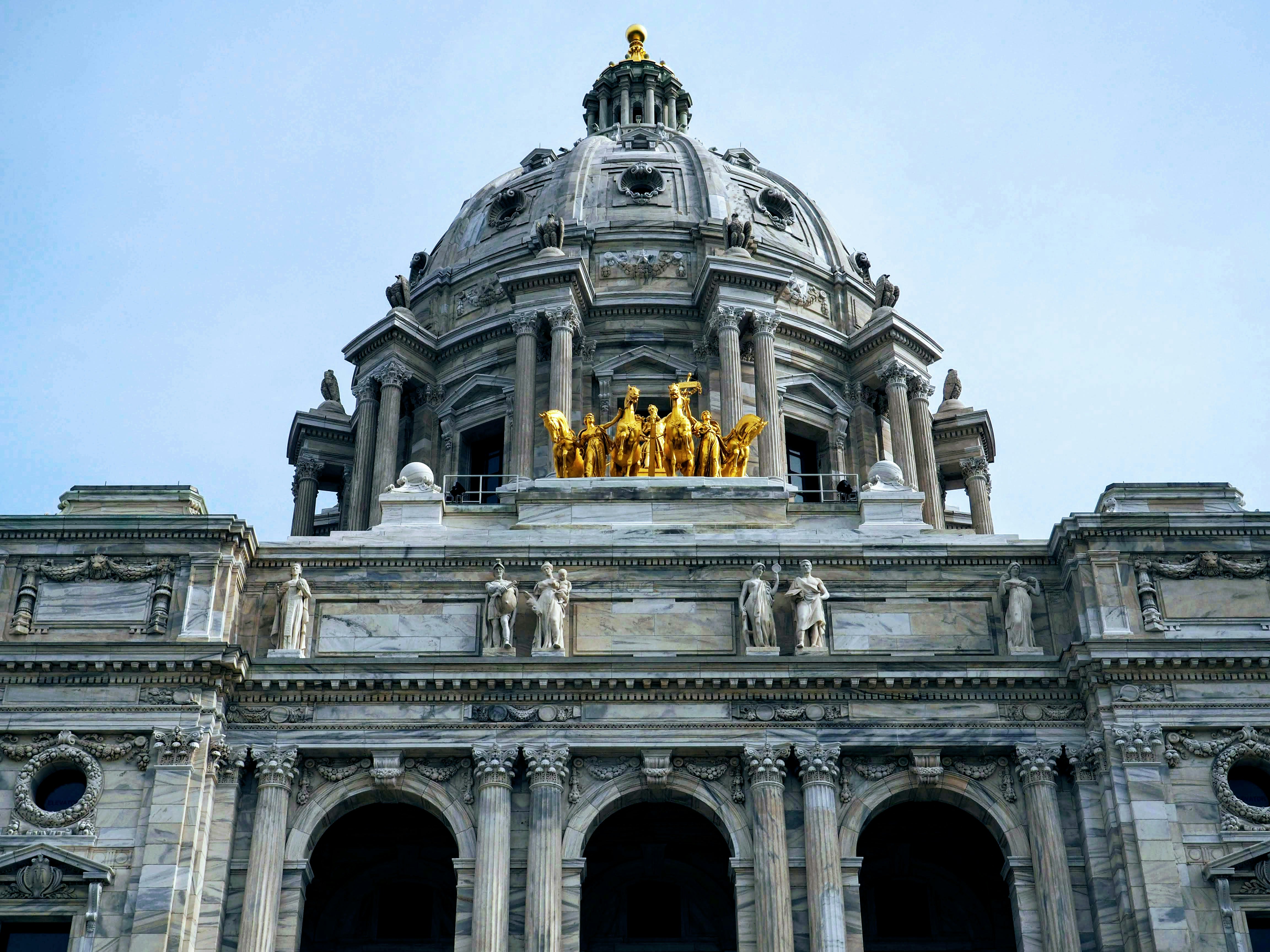 Minnesota State Capitol building dome with golden horses sculpture against blue sky