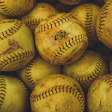 Collection of worn yellow softballs with black stitching and dirt marks