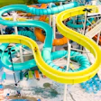 Aerial view of water park with turquoise and yellow spiral slides, pools, and recreational facilities surrounded by parking and landscaping