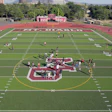 Aerial view of a maroon and green football field with players gathered at center during practice or event