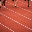 Athletes running on a red synthetic track during a competitive race event