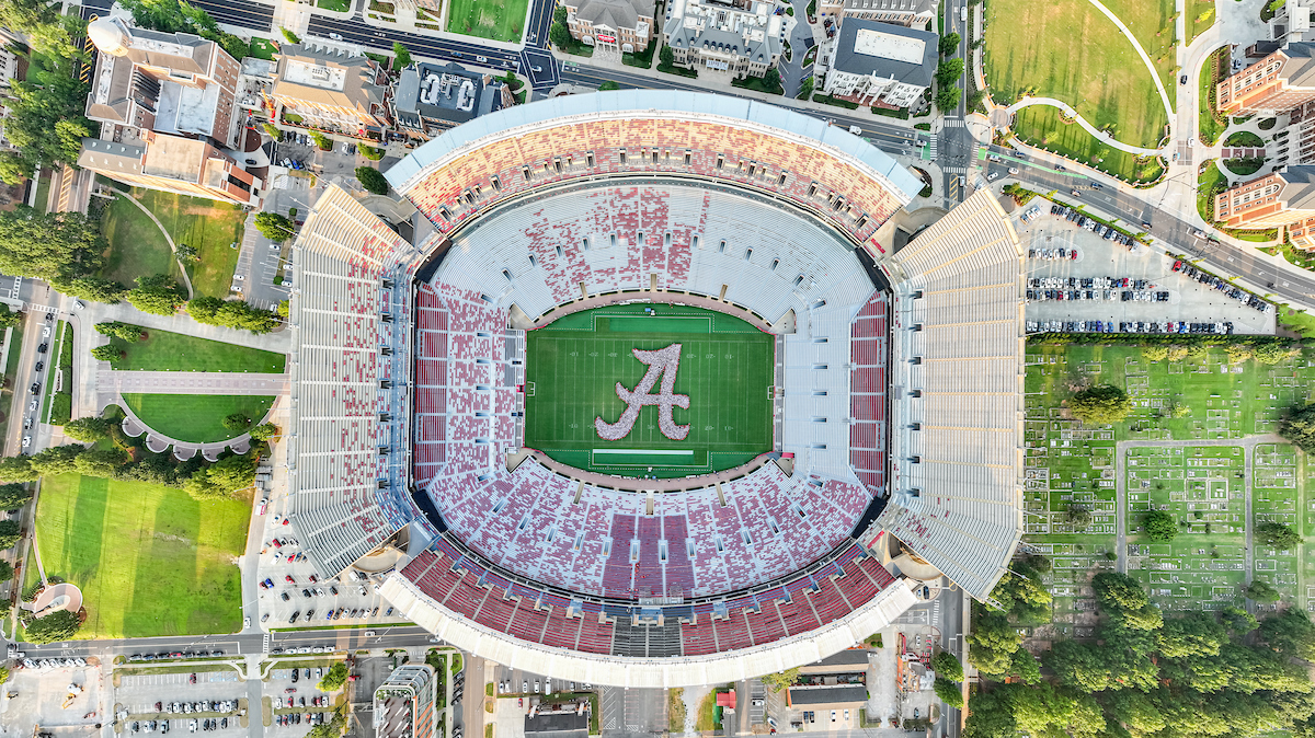 Aerial view of Bryant-Denny Stadium with crimson seating, green field, and Alabama 'A' logo
