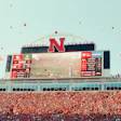 Memorial Stadium packed with red-clad fans during Nebraska football game with large scoreboard and N logo