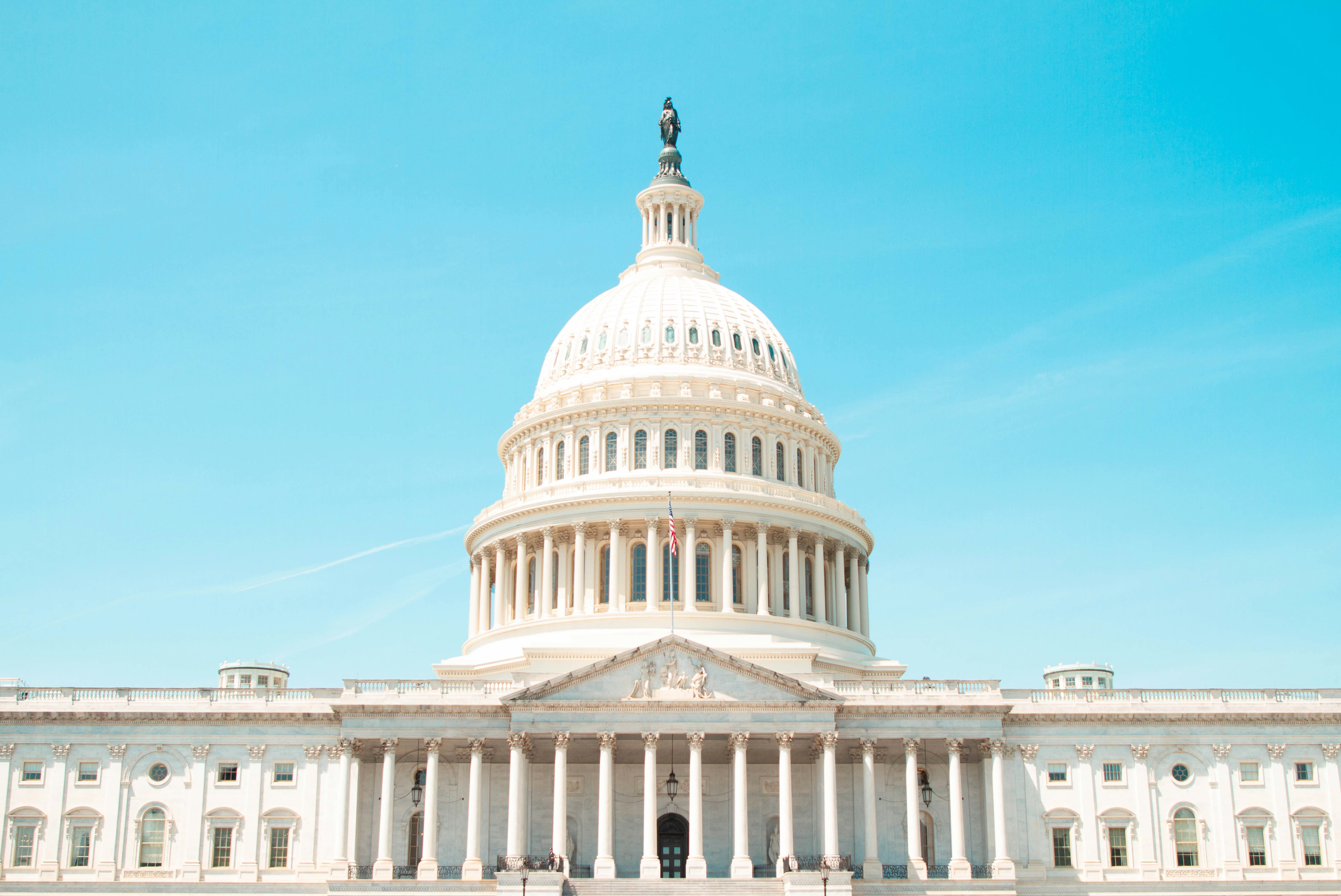 U.S. Capitol Building with white dome and neoclassical architecture against clear blue sky