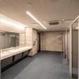 A community recreation center restroom with the following hygiene attributes: scrubbable ceiling tile, monolithic epoxy floor with integral cove base, touchless fixtures and accessories, and anti-microbial hardware.