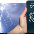 Smartphone displaying rainy weather forecast with 8°C temperature held against dramatic lightning storm background