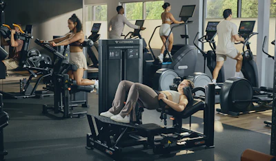 Modern gym facility with diverse members exercising on cardio and strength training equipment