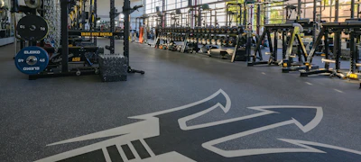 Geometric axe-shaped floor graphic in a CrossFit gym with weight equipment and training rigs in background