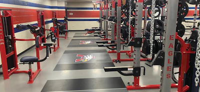 Modern gym interior with red and gray strength training equipment, weight machines, and black flooring