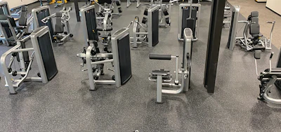 Modern gym interior with rows of exercise machines and equipment on gray flooring