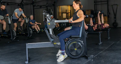 Group fitness class with participants exercising on Concept2 rowing machines in a modern gym facility