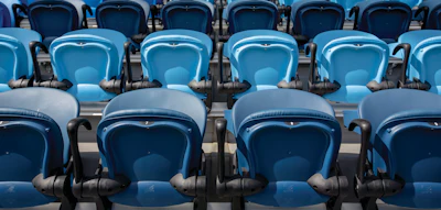 Rows of empty blue and dark blue stadium seats arranged in multiple tiers