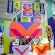 FIFA World Cup 2022 exhibition space with colorful geometric branding, large V-shaped logo installation, and visitors at interactive display area