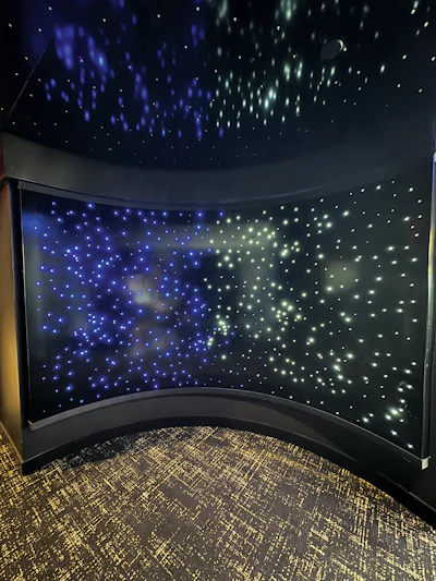 Curved LED light panel display with blue and white lights creating a starfield effect in a dark room