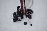 Overhead view of ice hockey players competing near the goal net with stick and puck on ice