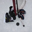 Overhead view of ice hockey players competing near the goal net with stick and puck on ice