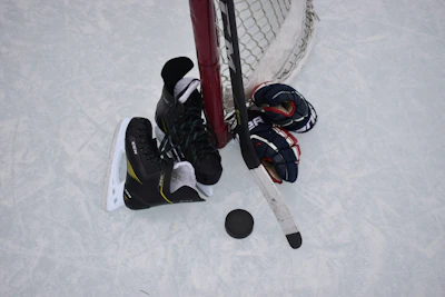 Overhead view of ice hockey players competing near the goal net with stick and puck on ice
