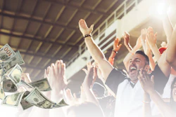 Excited group of people celebrating with arms raised as money falls around them in a bright, successful moment