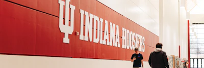 IU Indiana Hoosiers athletic facility wall signage with students in gymnasium
