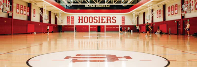 Indiana University Hoosiers basketball arena with red walls, polished wood floor, and IU logo at center court