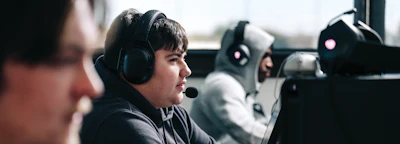 Young gamer wearing black headset at computer workstation in esports gaming facility