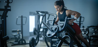 Woman exercising on stationary bike in modern gym with fitness equipment