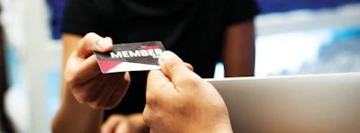 Two people examining a red and black membership card with white text