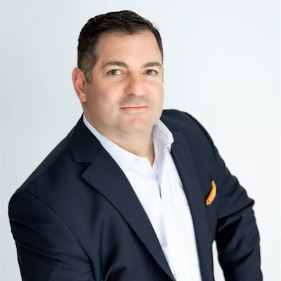 Professional headshot of a man in navy blazer and light blue shirt against white background
