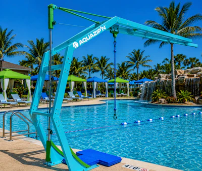 Turquoise Aquazion pool hoist with rope and platform at tropical resort pool with palm trees and loungers