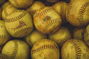 Collection of worn yellow softballs with black stitching and manufacturer markings