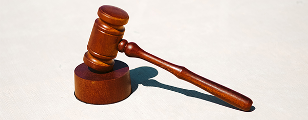 Wooden gavel and sound block casting shadow on white background