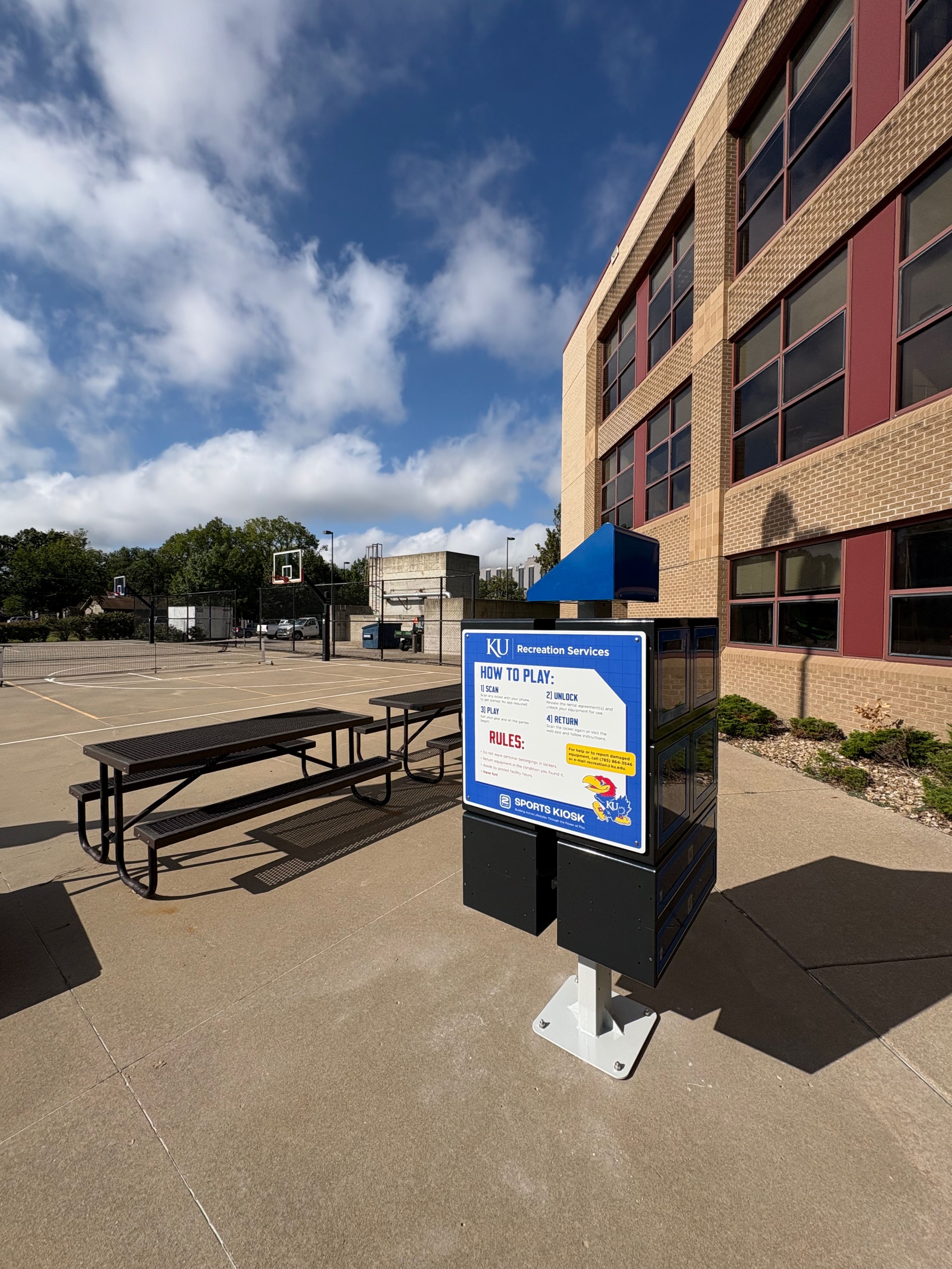 KU Recreation Services sign at outdoor basketball court with picnic table and brick building