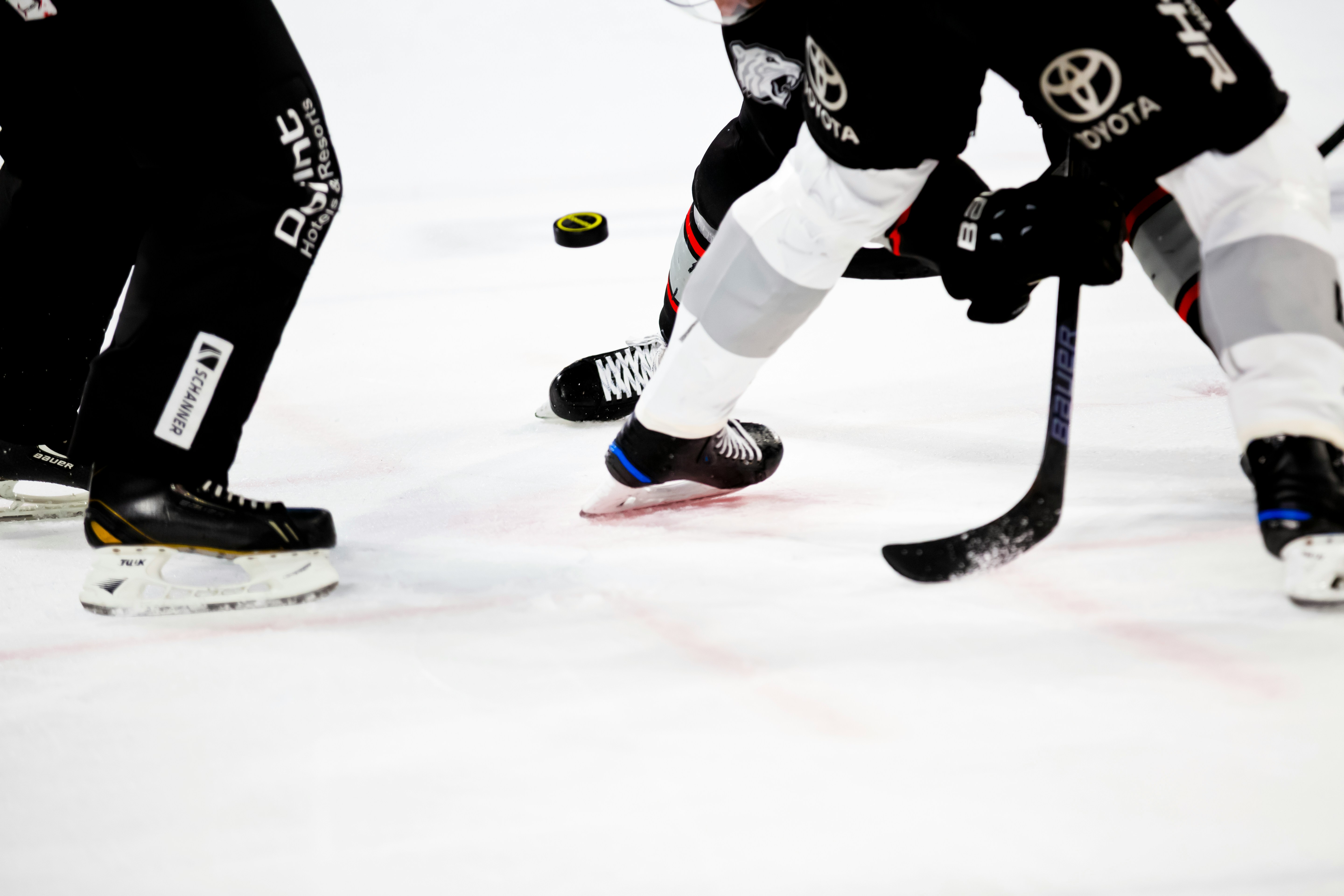 Ice hockey players in black uniforms with Toyota branding compete for the puck during a game.