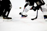 Ice hockey players in black uniforms with Toyota branding compete for the puck during a game.