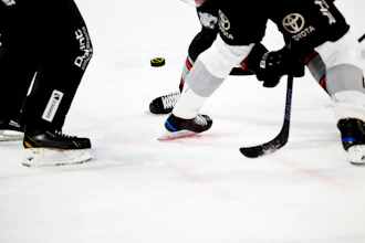 Ice hockey players in black uniforms with Toyota branding compete for the puck during a game.