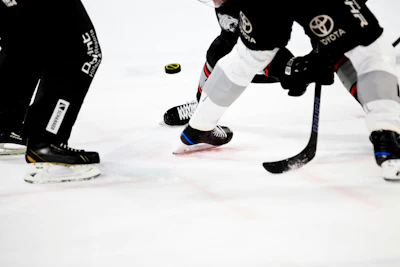 Ice hockey players in black uniforms with Toyota branding compete for the puck during a game.