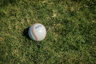 White baseball with red stitching on grass field