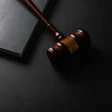 Wooden gavel with brass band next to open notebook on dark surface