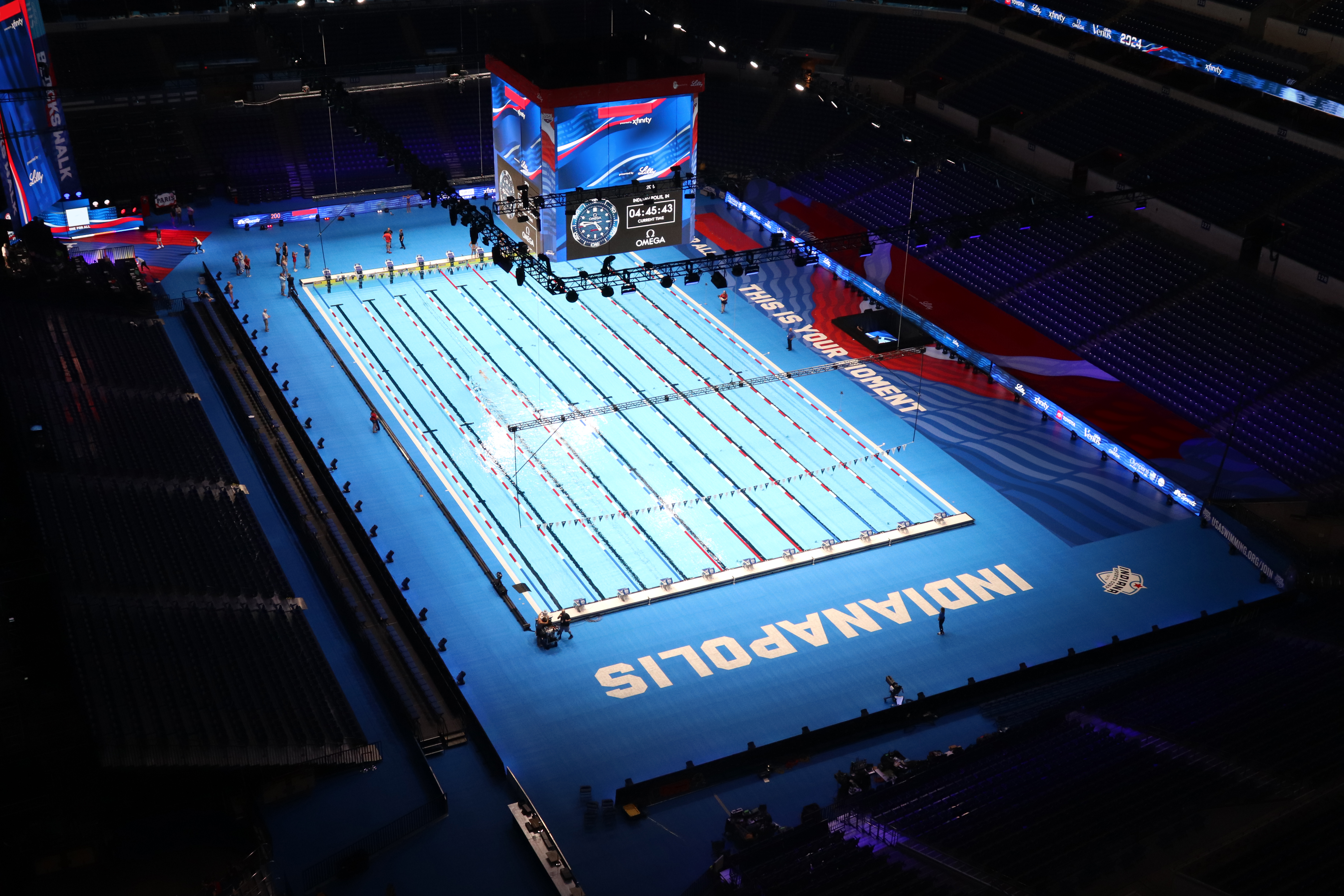 Olympic swimming competition pool with blue deck and lane dividers in an indoor stadium venue