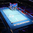Olympic swimming competition pool with blue deck and lane dividers in an indoor stadium venue
