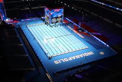 Olympic swimming competition pool with blue deck and lane dividers in an indoor stadium venue