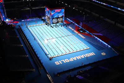 Olympic swimming competition pool with blue deck and lane dividers in an indoor stadium venue